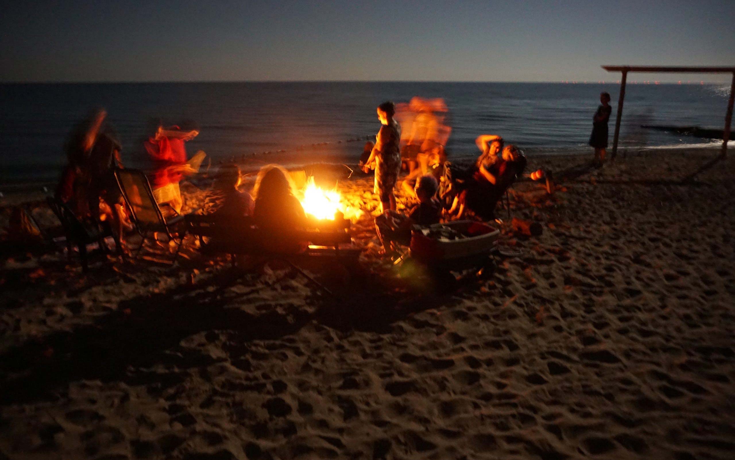 Campers gathered around a bonfire on the beach